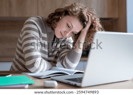 Tired female difficulty concentrating while working on laptop. Exhausted woman with low hemoglobin, burnout holding head in chronic fatigue, looking at documents feeling mentally, physically drained.