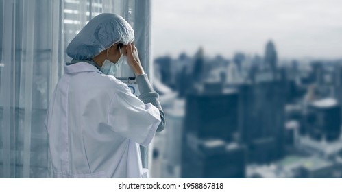 Tired Female Doctor Standing In Hospital, Healthcare And Coronavirus Covid-19 Pandemic Concept, Blurred Background.