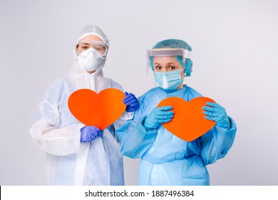 Tired Female Doctors In Virus Protection Gear Hold Paper Red Hearts In Hands. St Valentines Day, Charity And Giving Back. High Quality Photo