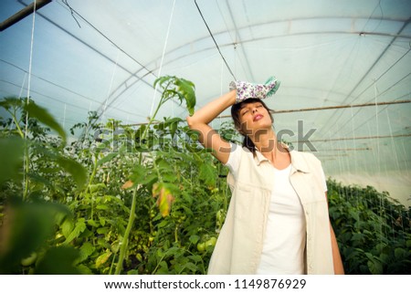 Tired female farmer in greenhouse
