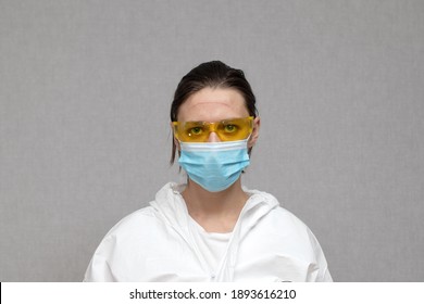 Tired Female Nurse On Yellow Protective Glasses With Marks On Her Face From A Medical Mask. Coronavirus Covid-19 Outbreak. Overworked Health Workers. Doctor In Protective Suit.