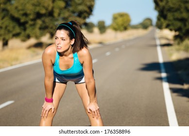 Tired Female Runner Sweating And Breathing After Running Hard In Countryside Road. Exhausted Sweaty Woman Recovering After Training On Hot Summer.