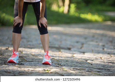 Tired Female Runner Taking A Rest After Running Hard In Countryside Road. Sweaty Athlete After Marathon Training In Country Road. 