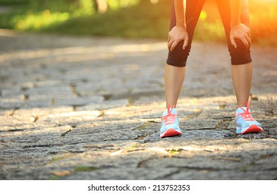 Tired Female Runner Taking A Rest After Running Hard In Countryside Road. Sweaty Athlete After Marathon Training In Country Road. 