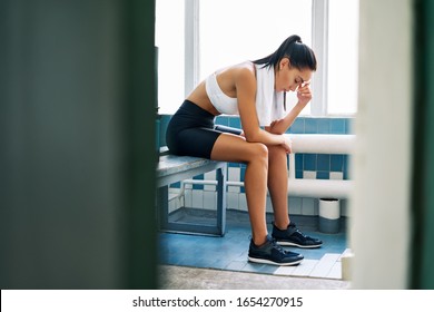 Tired fit woman with a towel in the locker room after hard workout. Stress, sport, failure concept                       - Powered by Shutterstock