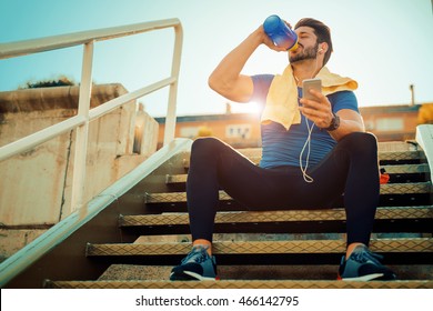 Tired Fitness Man Sweating Taking A Break Listening To Music On Phone After Difficult Training.Fitness,sport,training And Lifestyle Concept.