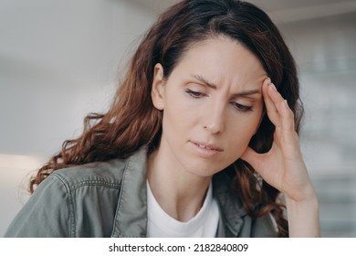 Tired Freelancer Is Working And Getting Fatigue. Exhausted European Woman Is Studying Hard. Lady Has A Headache And Touches Face With Hand. Stress And Problem From Remote Work Or Study.