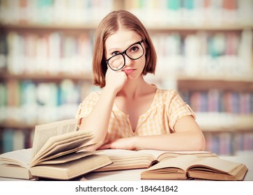 tired funny crazy  girl student with glasses reading books in the library