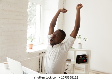 Tired Funny Male African American Person Yawning And Stretching In Office Chair, Feeling Tired After Long Hours Of Hardworking, Exhausted By Too Much Work. Boredom, No Motivation Concept, Work Done