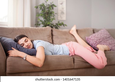 Tired Funny Young Woman In Summer Everyday Clothes Stretches Out And Sleeps On Sofa At Home. Female Student Asleep In Morning In Living Room After Party, Taking Break For Short Sleep In Middle Of Day