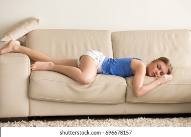 Tired Funny Young Woman In Summer Everyday Clothes Stretches Out And Sleeps On Sofa At Home. Female Student Asleep In Morning In Living Room After Party, Taking Break For Short Sleep In Middle Of Day