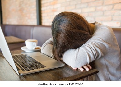 Tired girl sleeping beside a cup of coffee
