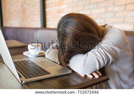 Tired girl sleeping beside a cup of coffee