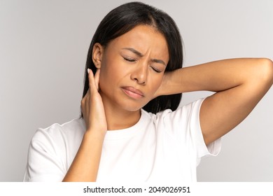 Tired girl suffer from neck pain, pinched nerve in her back. African woman has spinal problem, muscle inflammation, rheumatoid pain isolated on studio grey background. incorrect posture, fibromyalgia.