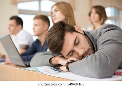 Too tired. Handsome male tired student sleeping on his books during lecture at university classroom exams session tired education lazy boring college sleep people school napping overworking concept - Powered by Shutterstock