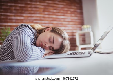 Tired hipster businesswoman sleeping on her desk on office