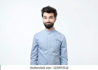 Tired Hispanic Man In Blue Shirt With Beard Looking Confusedly At Camera Like He Has No Idea What Is Going On And Try To Smile