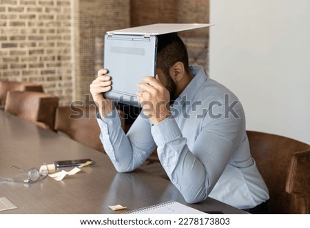 Tired Hispanic Man Working Remotely from Office Falls Asleep on the Job Tired Exhausted Holding Laptop agains his face Angry Fed up Despaired 