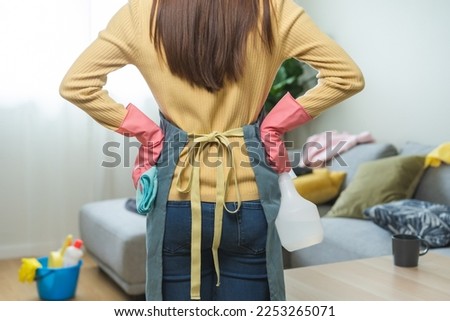 Tired household clean up, frustrated housekeeper asian young woman, girl stand and look many pillow on sofa, couch cleaning in living room at home. Messy maid or housewife organizing dirty and untidy.