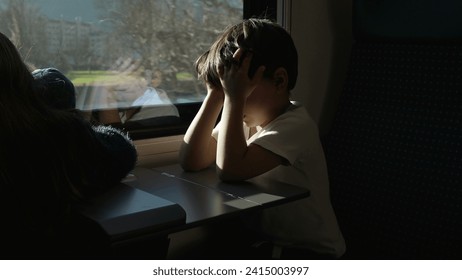 Tired Litle boy rubbing eyes and face while on a moving train hiding from sun rays. Passenger Child waking up from nap while traveling - Powered by Shutterstock