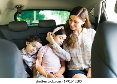 Tired Little Kids Falling Asleep In The Car With Their Mom After Playing Outside All Day. Caring Young Woman And Mom Caressing Her Daughter's Face