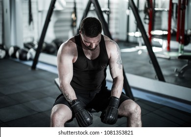 Tired male boxer sitting on stool in gym