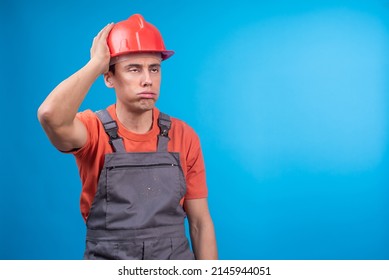 Tired Male Builder In Uniform Touching Hardhat