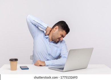 Tired Male Employee Sitting Office Workplace, Touching Sore Back Neck, Massaging Hurting Shoulders, Painful Stiff Muscles, Feeling Exhausted Fatigued. Indoor Studio Shot Isolated On White Background