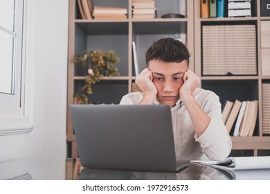 Tired male student or worker sit at home office desk look in distance having sleep deprivation, lazy millennial man distracted from work feel lazy lack motivation, thinking of dull monotonous job