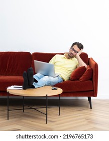 Tired man fell asleep on the couch with laptop on his legs. Work from home and online job concept