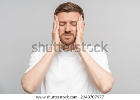 Tired man holds his head suffering from pain. Middle aged male suffers from terrible pain in head. Headache, migraine, overwork, illness, stress. Isolated on studio gray background