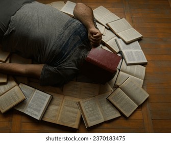 Tired man lying on wooden parquet floor with book on his face. busy Man read book. empty book cover surface. mockup. pile of many books lie around male. unrecognizable person. mock up.              - Powered by Shutterstock