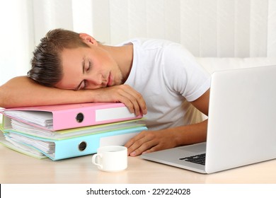 Hombre cansado con bloc de notas y muchas carpetas duermen en la tabla