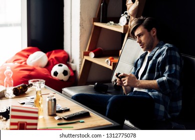 Tired Man Playing Video Game In Messy Living Room