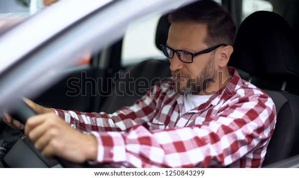 Tired man sitting in car suffering neck\
discomfort, spinal problem,\
cervicalgia