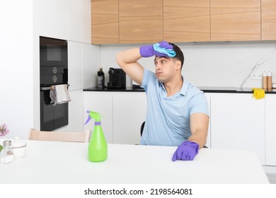 Tired Man Sitting In The Kitchen After Cleaning House. Exhausted Household Concept