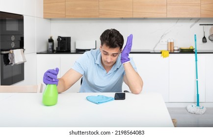 Tired Man Sitting In The Kitchen After Cleaning House. Exhausted Household Concept