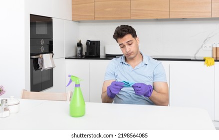 Tired Man Sitting In The Kitchen After Cleaning House. Exhausted Household Concept