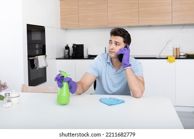 Tired Man Sitting In The Kitchen And Resting After Exhausted Cleaning House