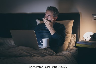 Tired man sleeping on bed after hard works with laptop until late at night. Bored boy sitting in bedroom use online devices. Smart working, home school, internet lifestyle new technology concept - Powered by Shutterstock