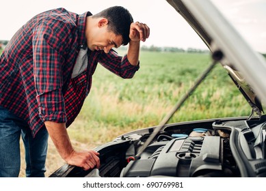 Tired man tries to repair a broken car - Shutterstock ID 690769981