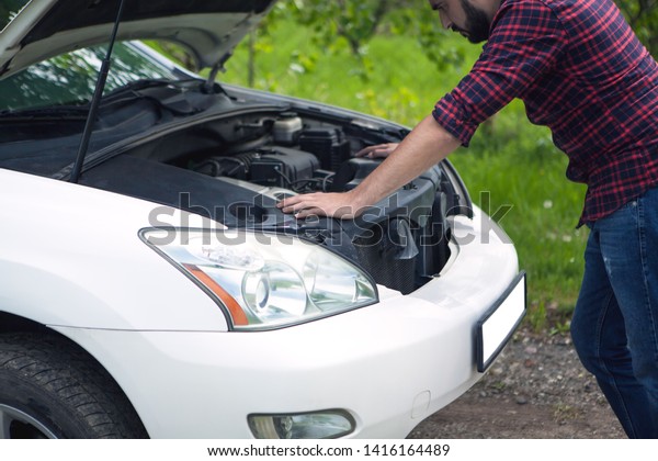 Tired man trying to fix a\
broken car