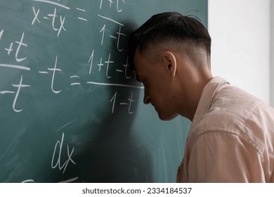 Tired Math teacher near chalkboard in classroom - Powered by Shutterstock