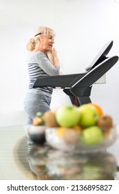 Tired Mature Woman Wiping Sweat With Towel While Walking On The Treadmill At Home