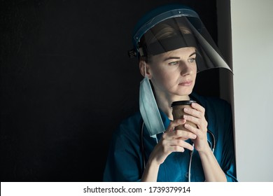 tired medical worker doctor holding a paper cup of coffee after taking a large number of patients due to the epidemic of coronavirus - Powered by Shutterstock