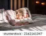 Tired middle aged woman lying in bed can