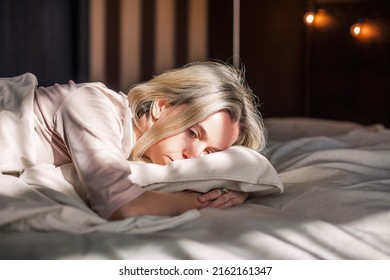 Tired middle aged woman lying in bed can't sleep late at morning with insomnia. Adult lady sick or sad depressed sleeping at home.