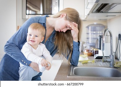 Tired Mom With Baby In Her Arms Standing By The Sink