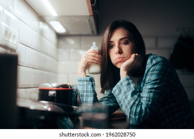 Tired Mother Holding A Milk Baby Bottle At Night. Exhausted Sleepy Mom Preparing Formula For Night Feeding The Newborn 
