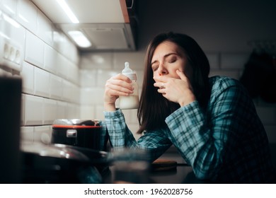 Tired Mother Holding A Milk Baby Bottle At Night. Exhausted Sleepy Mom Preparing Formula For Night Feeding The Newborn 
